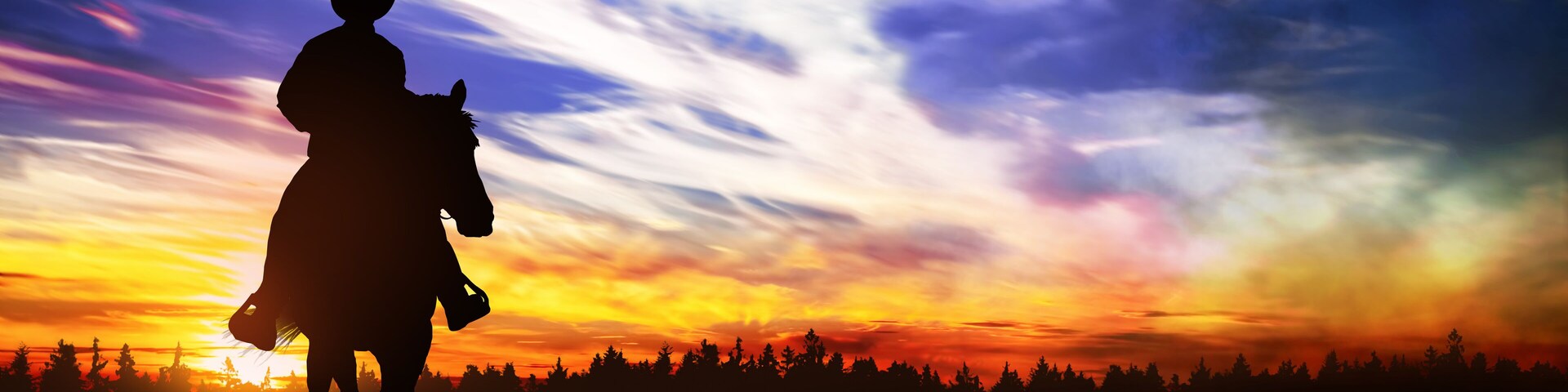 cowboy riding in the hills at sunset