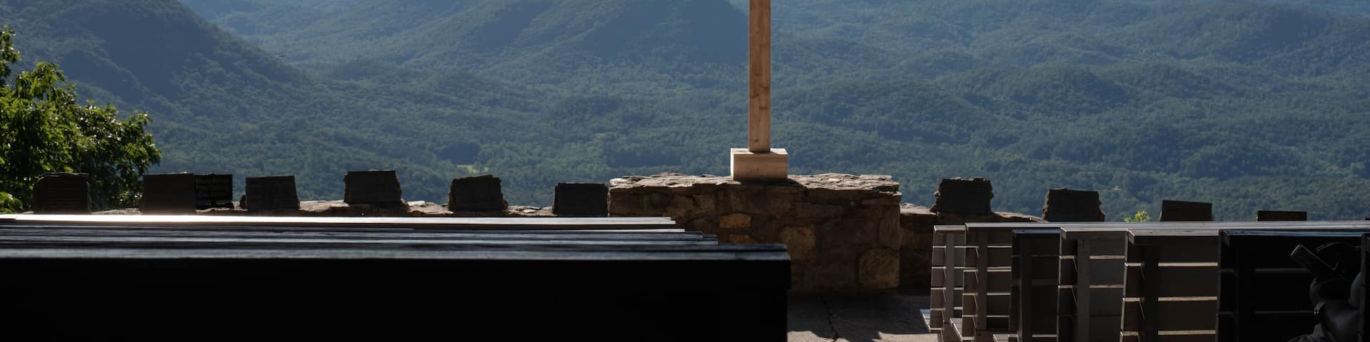 A wooden cross with a sign above it reading 'I WILL LIFT UP MY EYES TO THE HILLS... Psalm 121:1' against a backdrop of a mountainous landscape.
