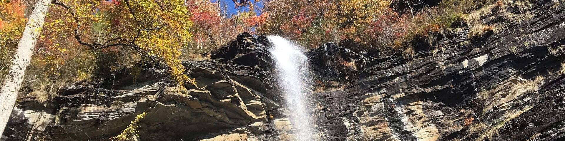 A waterfall cascading down a rocky cliff surrounded by autumn-colored trees.