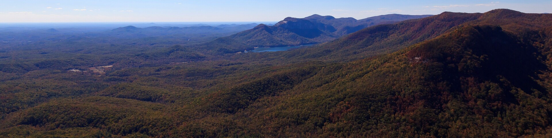 Un paisaje montañoso con bosques densos y un cielo azul despejado.