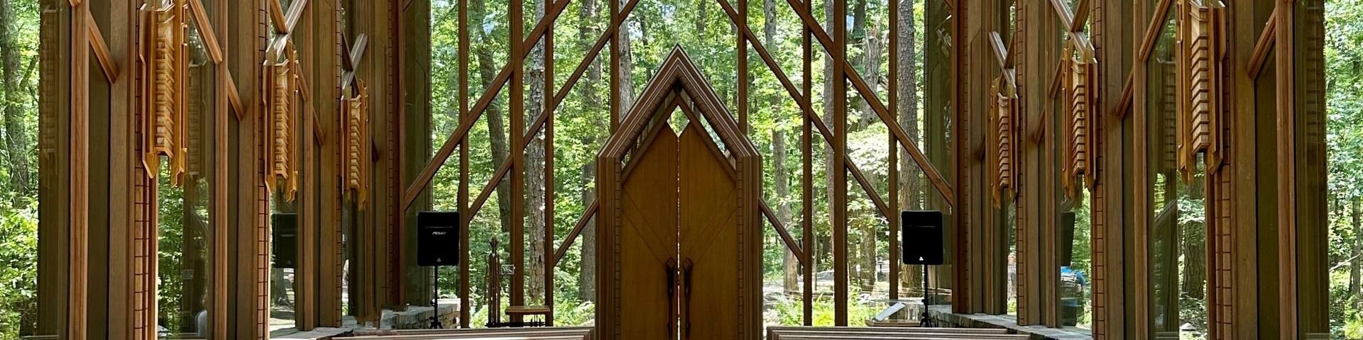 A wooden structure with a high ceiling and a central aisle leading to a door.