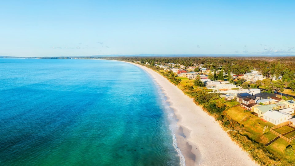 A coastal town with a beach and houses along the shoreline.