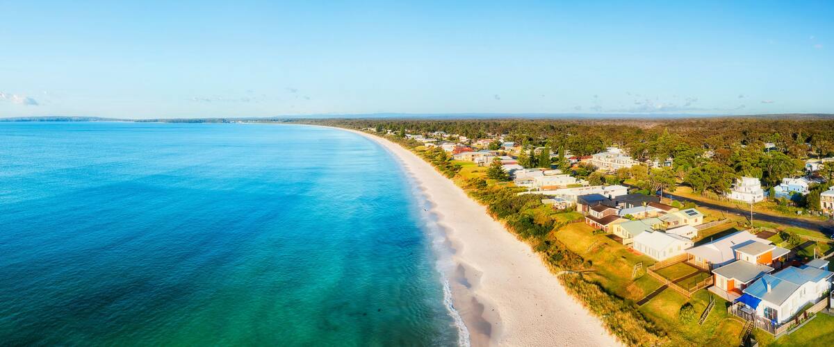 A coastal town with a beach and houses along the shoreline.
