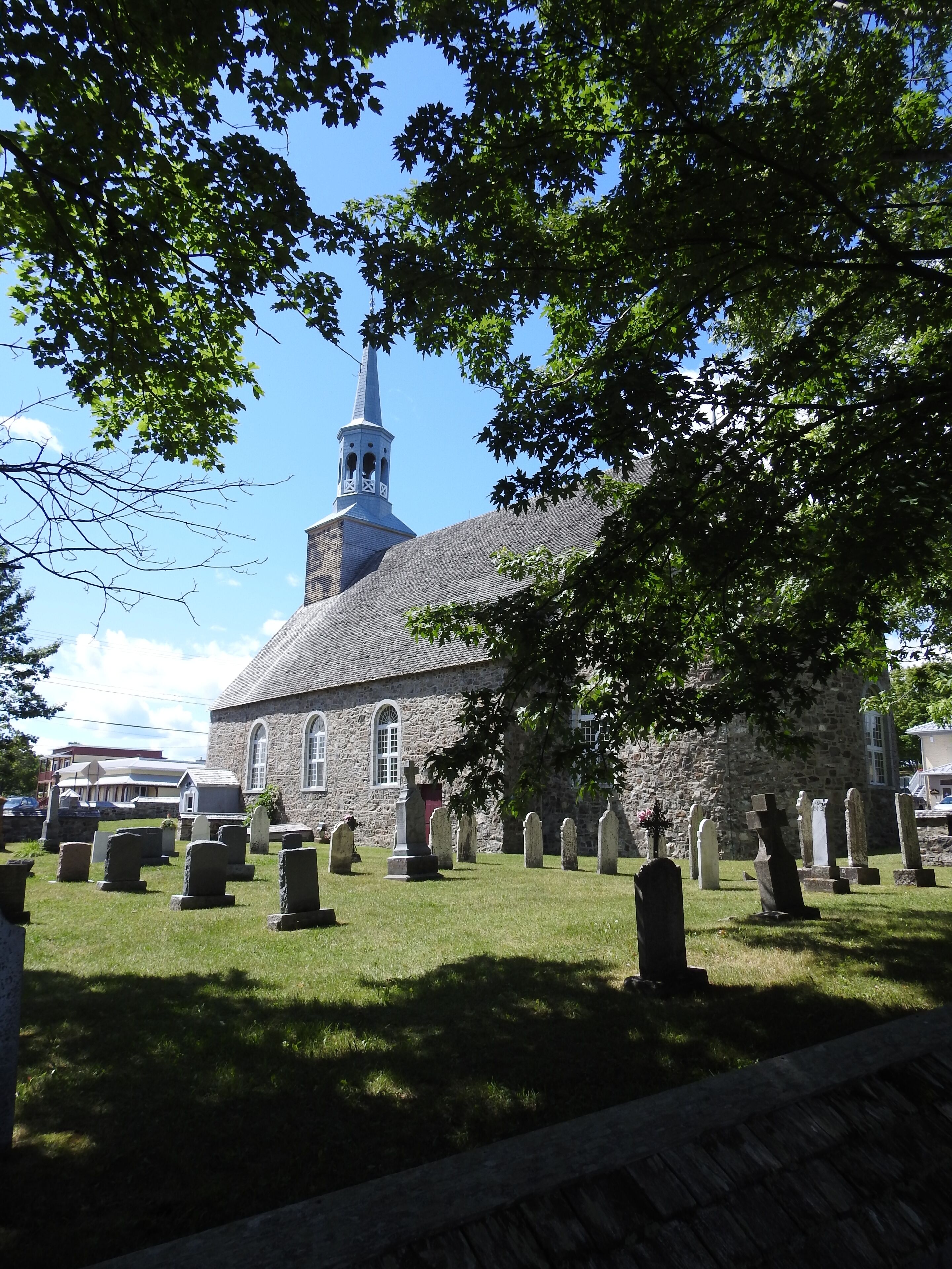 A church with a steeple and gravestones in the foreground.