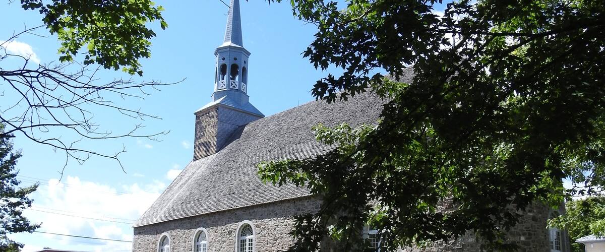 A church with a steeple and gravestones in the foreground.