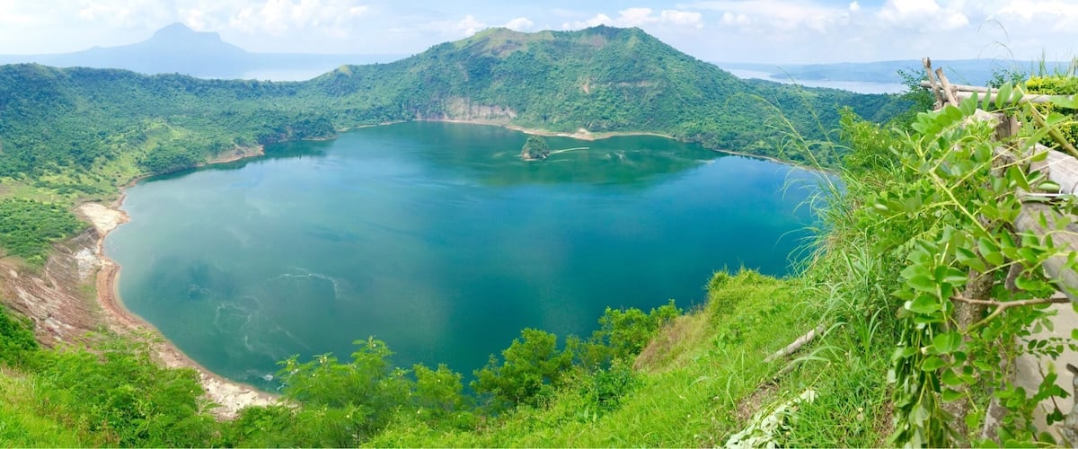 Un lago grande y circular rodeado de colinas y montañas verdes y exuberantes.