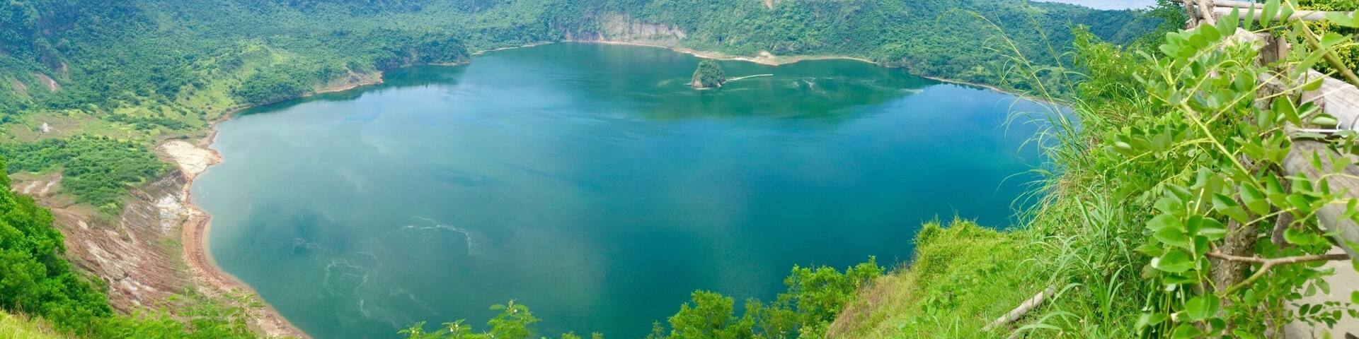 A large, circular lake surrounded by lush green hills and mountains.