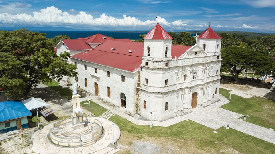 A historic white building with red roofs and a circular courtyard.