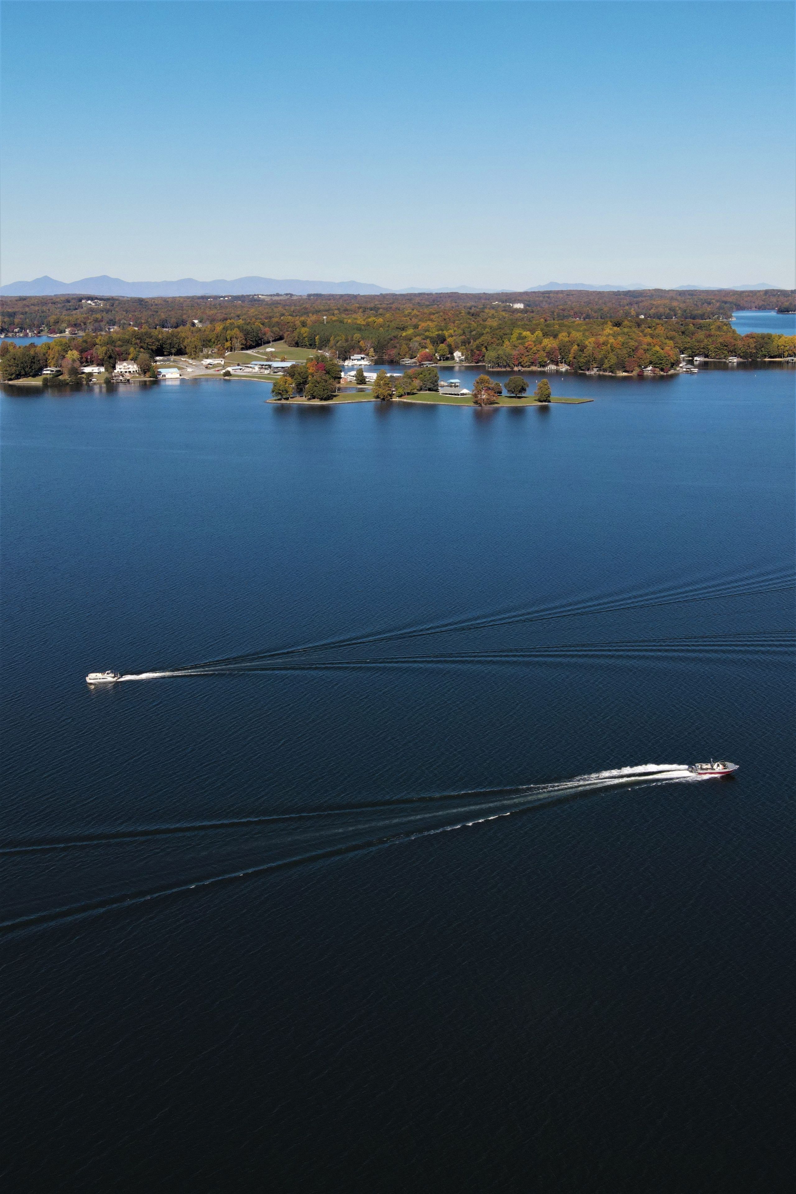 A large body of water with two boats creating wake patterns.
