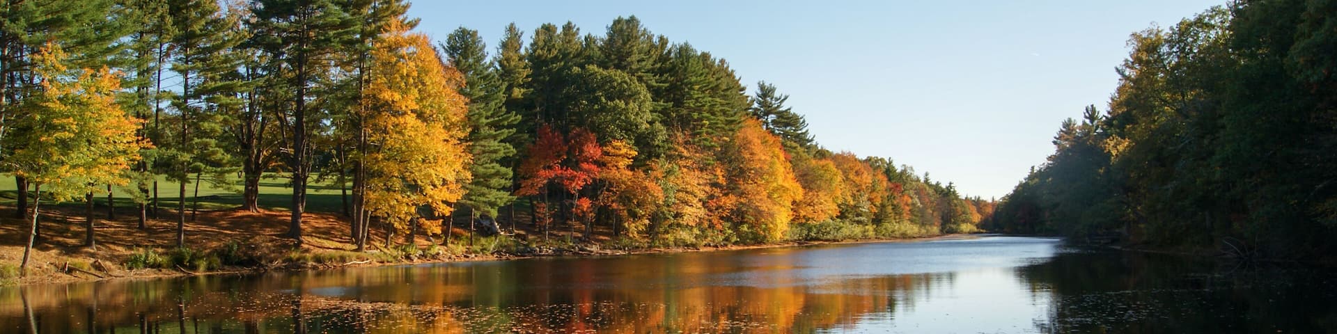 A calm river reflecting autumn trees.