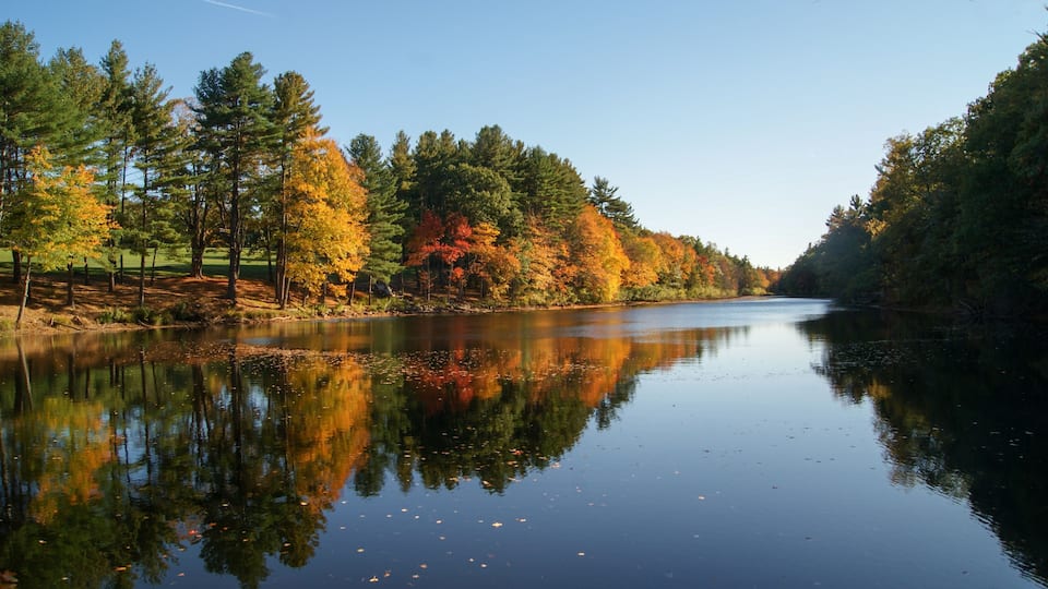 A calm river reflecting autumn trees.