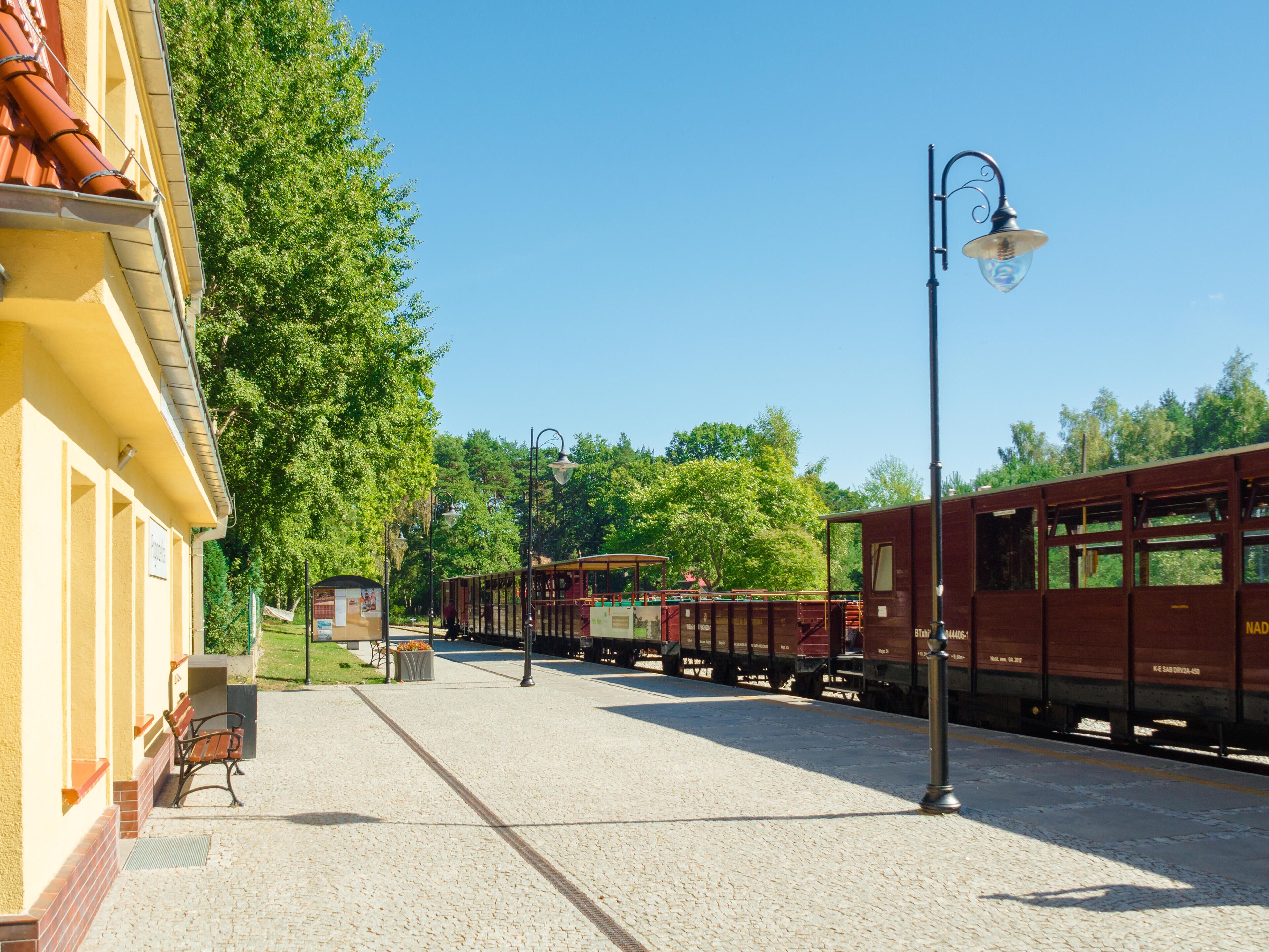 A train station platform with a vintage train, a bench, and a lamppost.