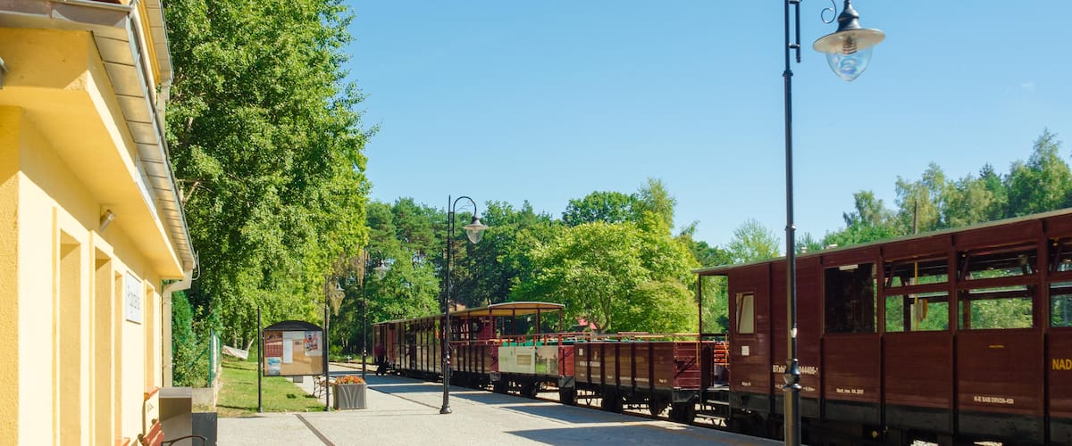 A train station platform with a vintage train, a bench, and a lamppost.