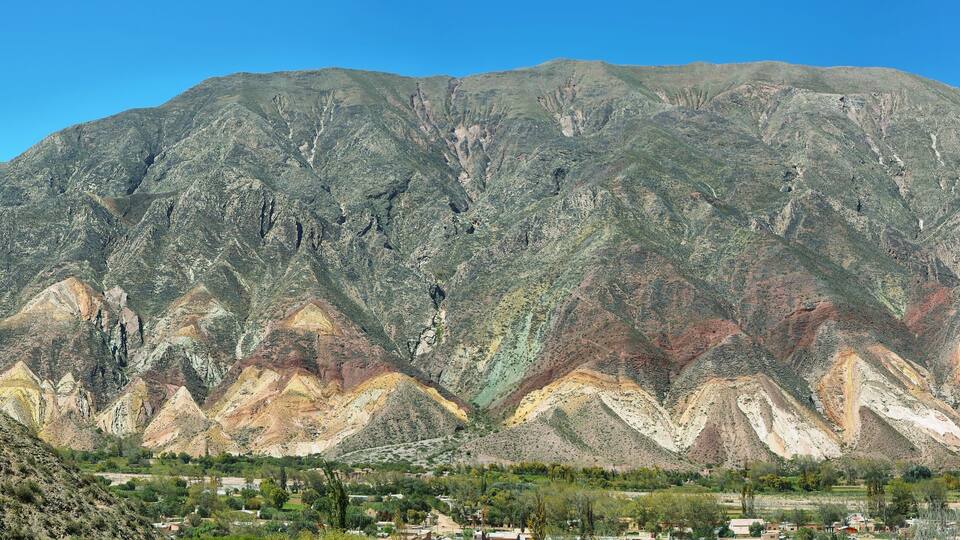 A mountain range with distinct geological layers and a valley below.