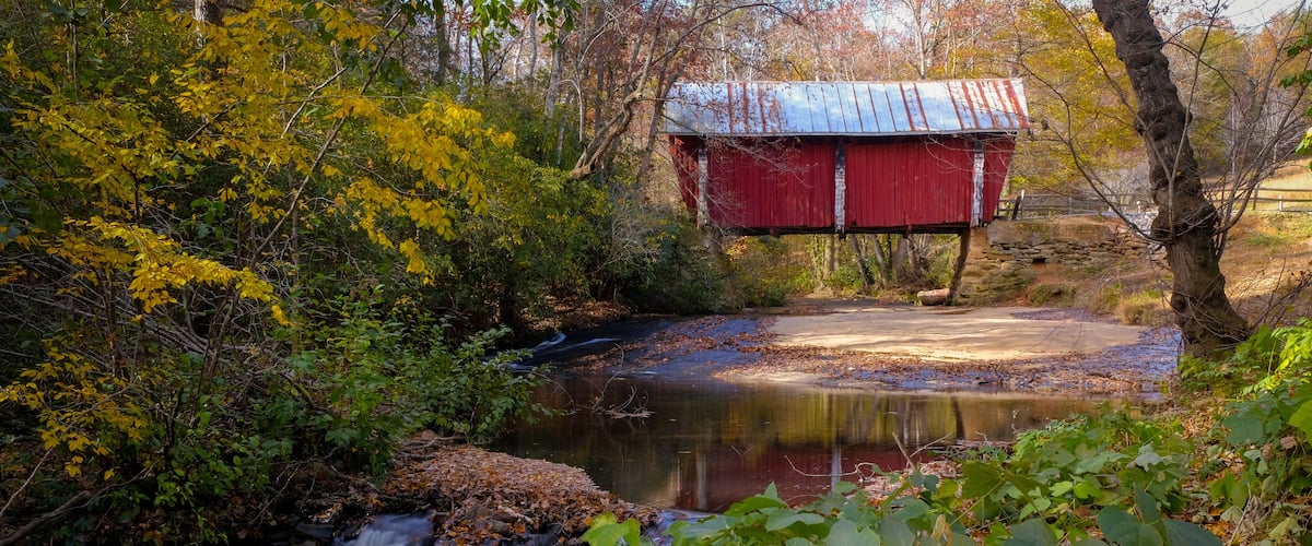 Campbell's covered bridge in Greer, South Carolina, USA with fall foliage and smooth water in stream