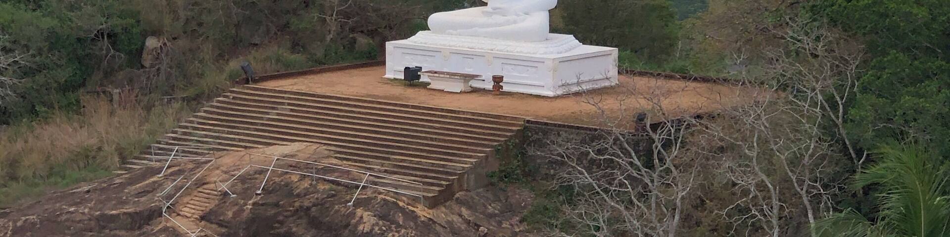 A white statue on a hilltop with a view of a valley below.