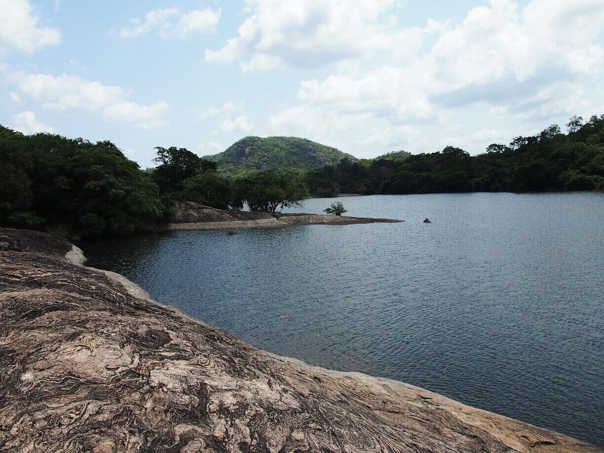 A calm lake surrounded by rocky terrain and dense forest.