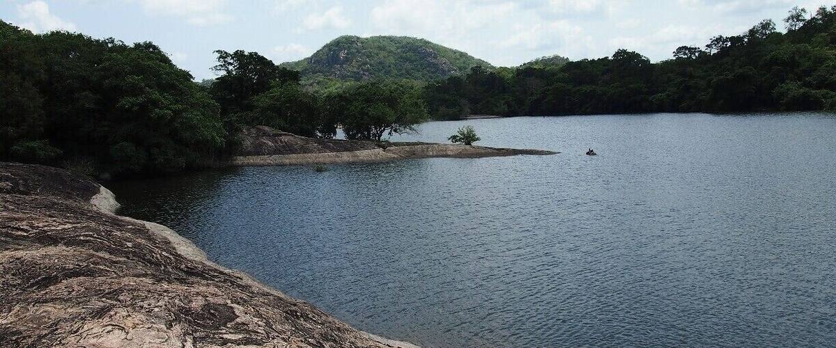 A calm lake surrounded by rocky terrain and dense forest.