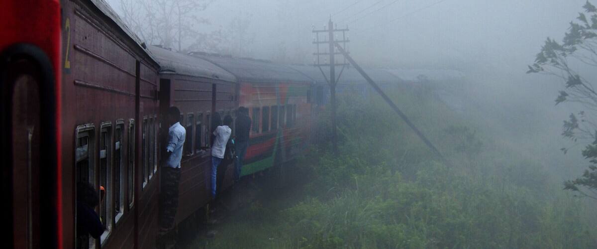 A train in a foggy, rural setting with passengers boarding.