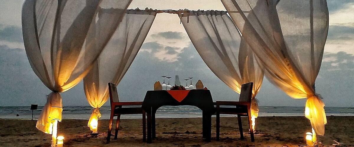 A beach ceremony setup with a table and chairs under a canopy.