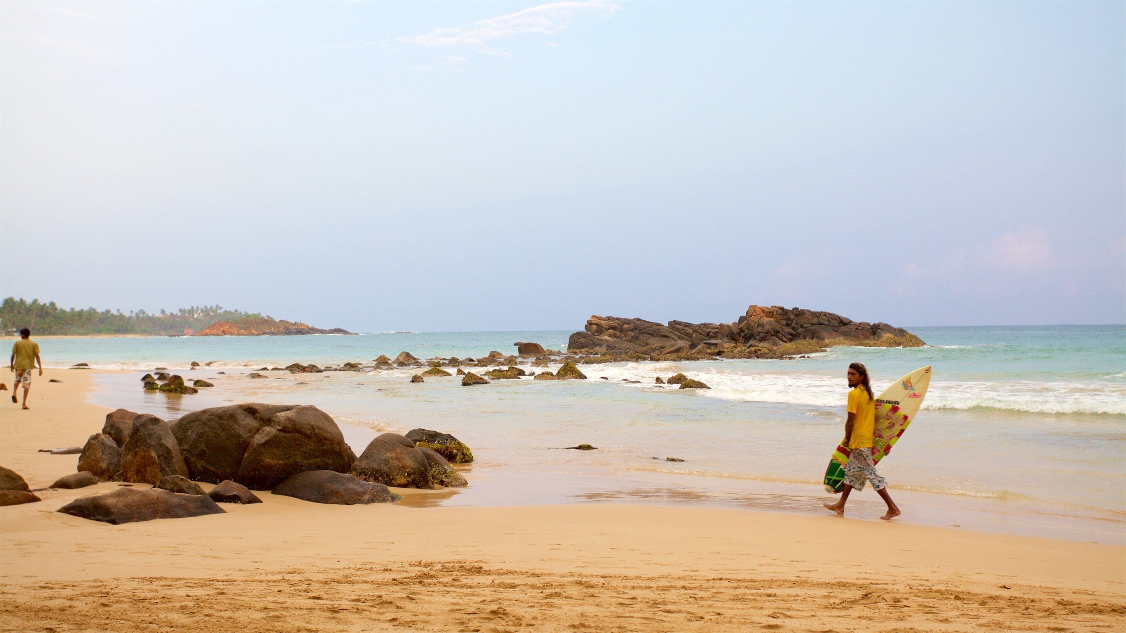 A beach with large rocks and calm water.