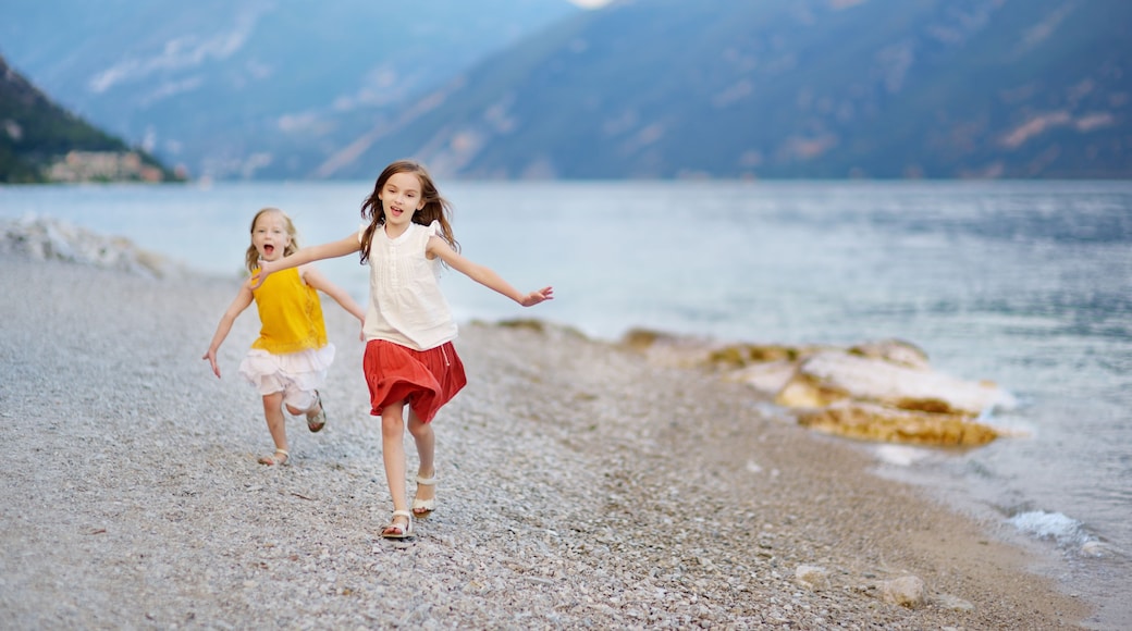 Two cute little sisters having fun on a beach of Limone sul Garda, a small town and comune in the province of Brescia, Italy