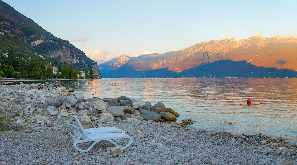 evening scenery gravel beach lake Gardasee, tourist resort Gargnano, last sun over Montebaldo