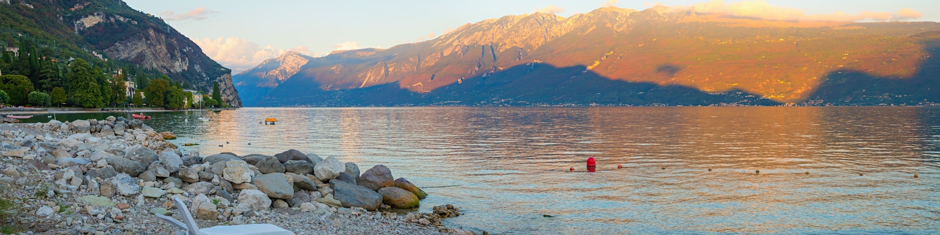 evening scenery gravel beach lake Gardasee, tourist resort Gargnano, last sun over Montebaldo