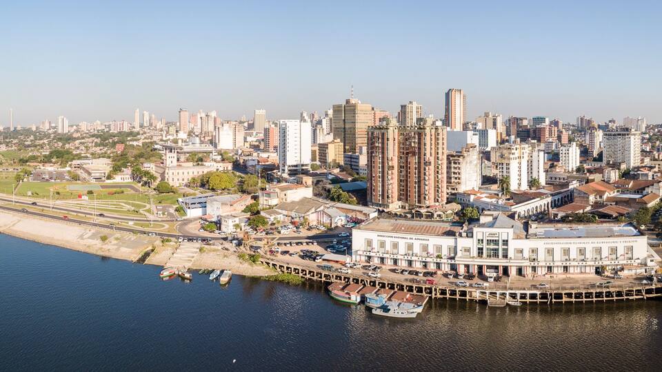 A coastal cityscape with a marina, high-rise buildings, and a clear sky.