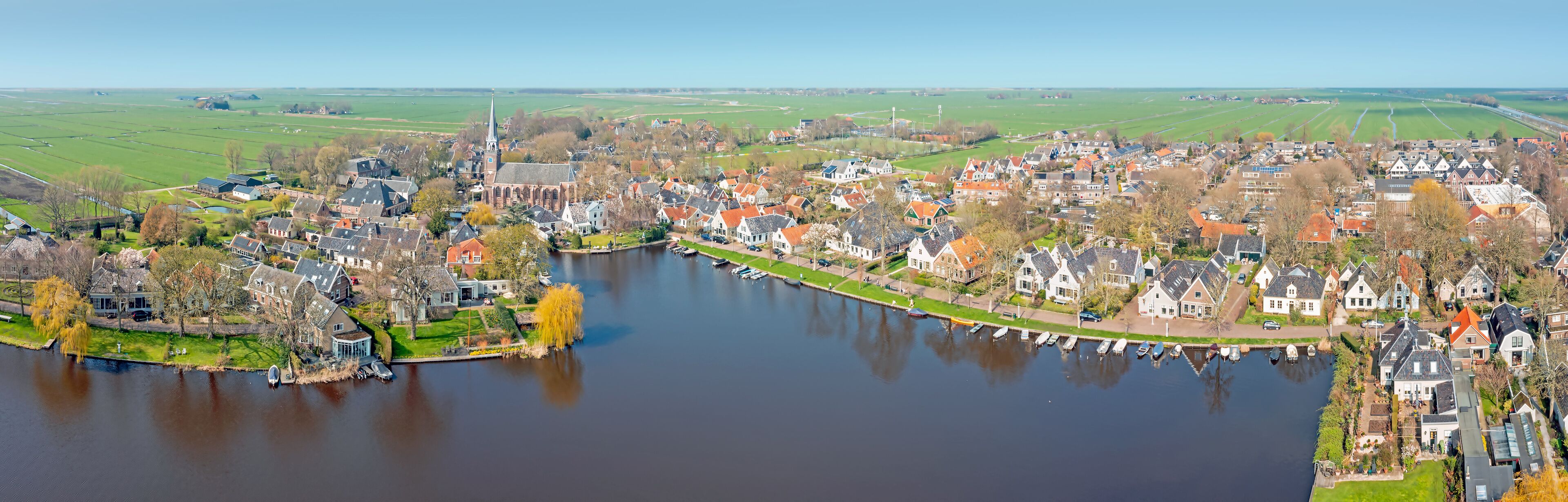 A riverside town with historic houses, a church, and expansive fields.