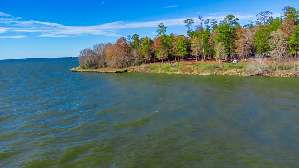 A calm lake with a forested shoreline and a clear blue sky.