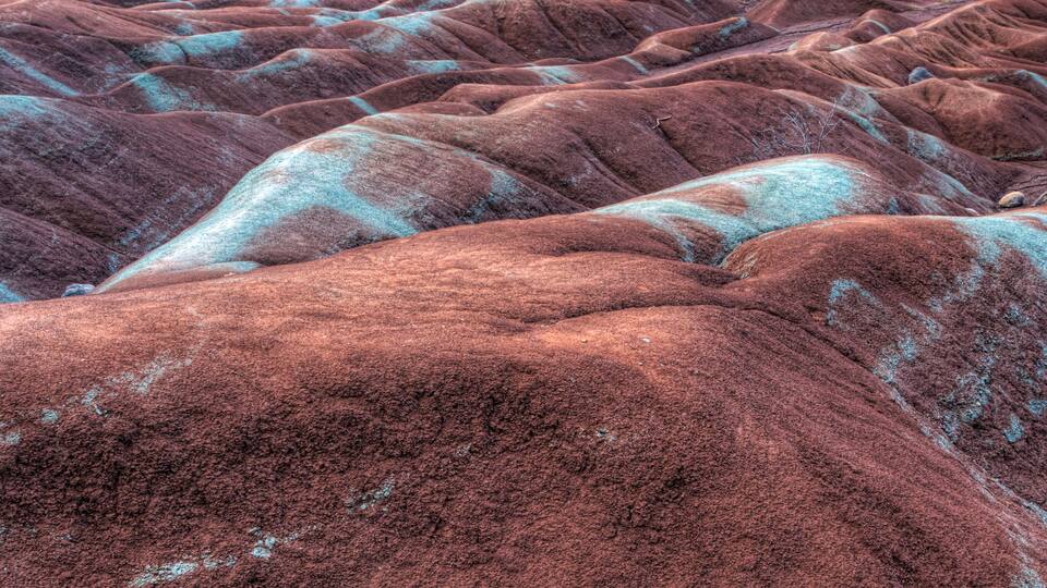 A close-up of a textured, undulating landscape with reddish-brown and turquoise hues.