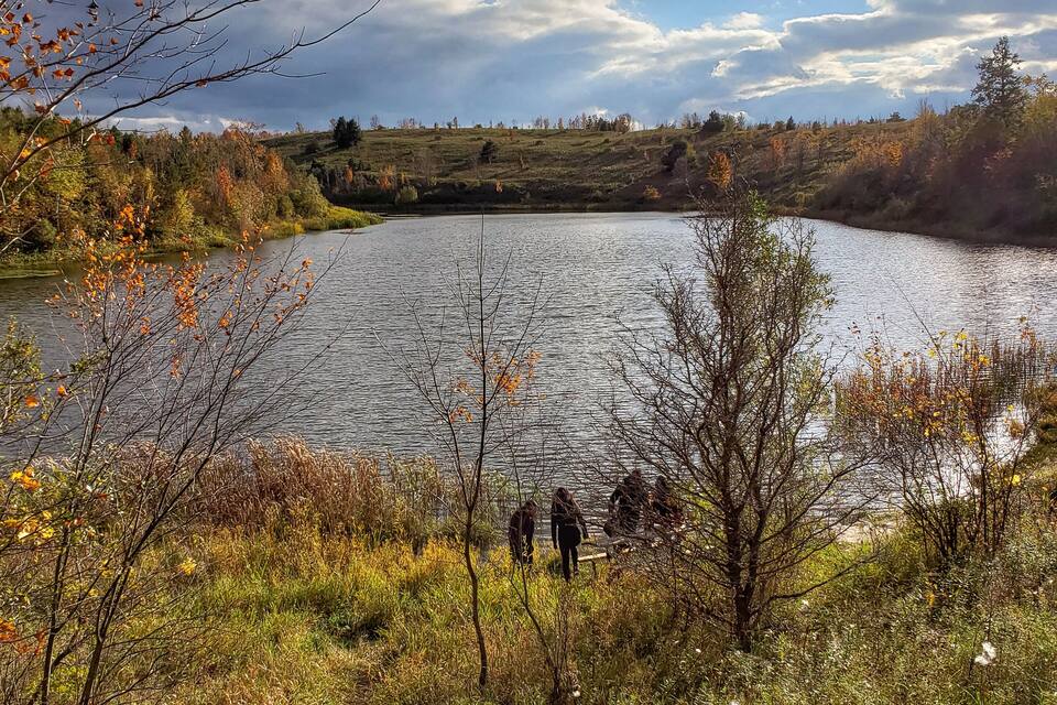 A lake surrounded by autumn foliage and a cloudy sky.