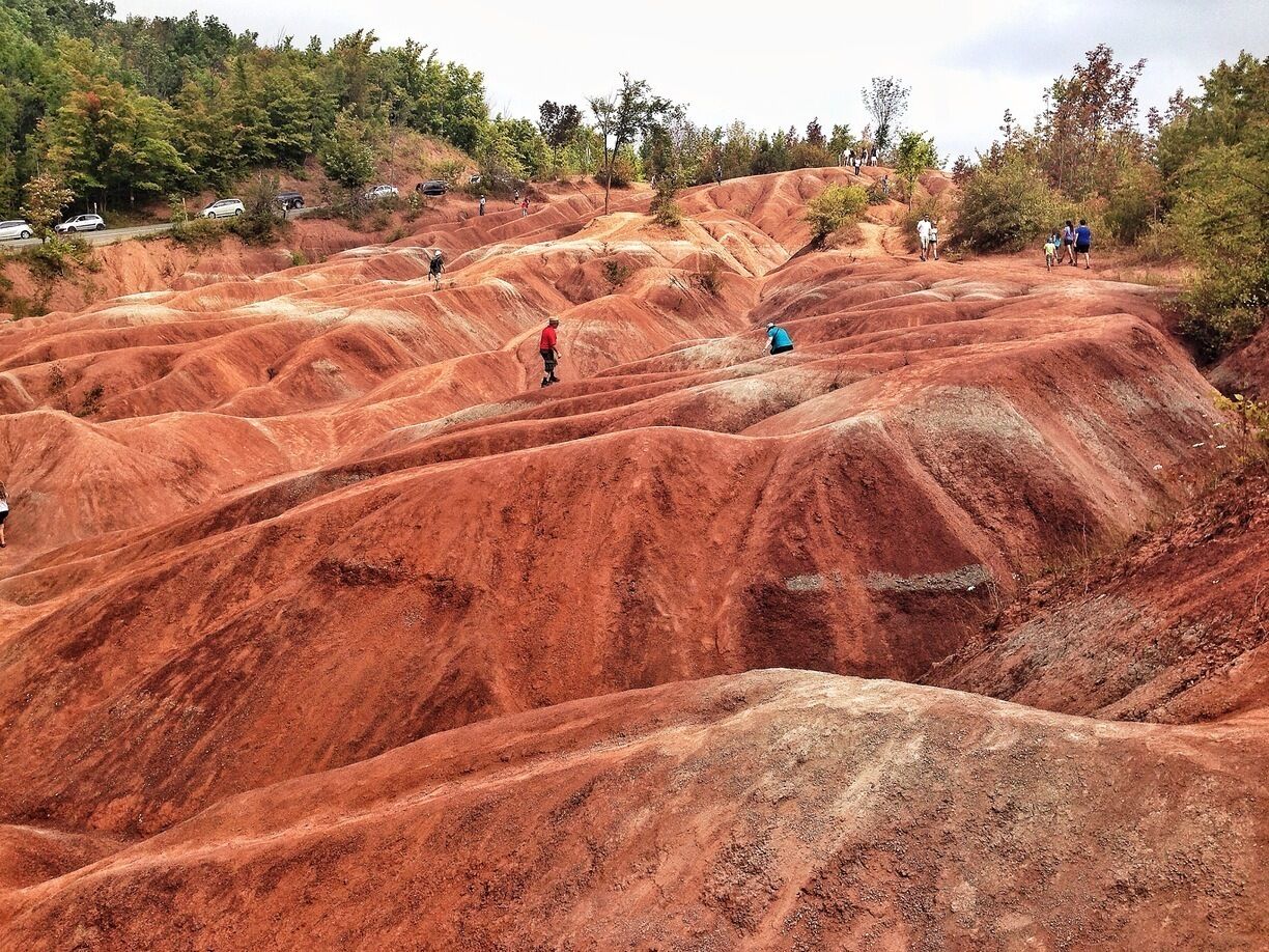 A red earth landscape with people hiking.