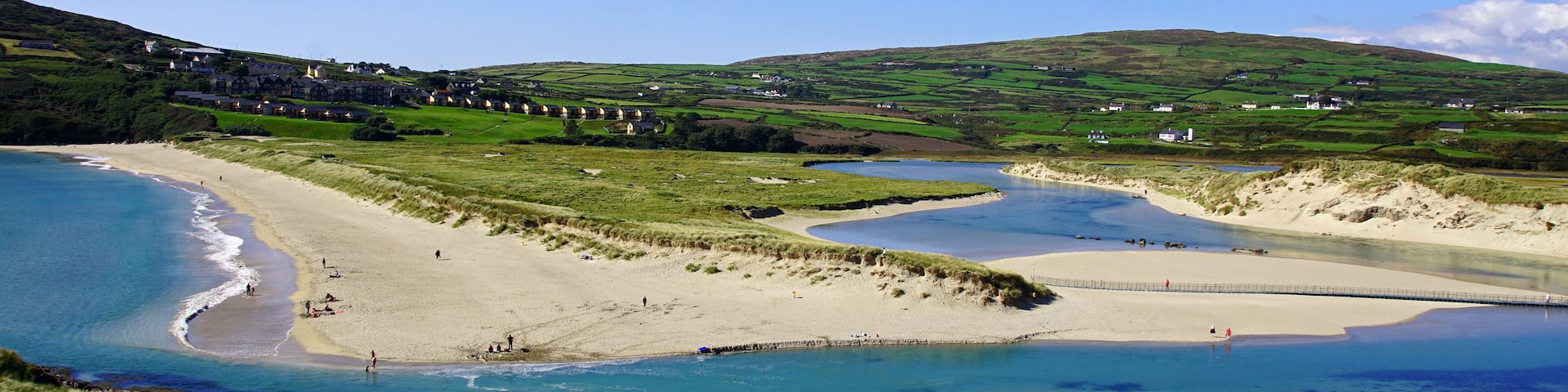 A coastal landscape with a beach, a river, and rolling hills.