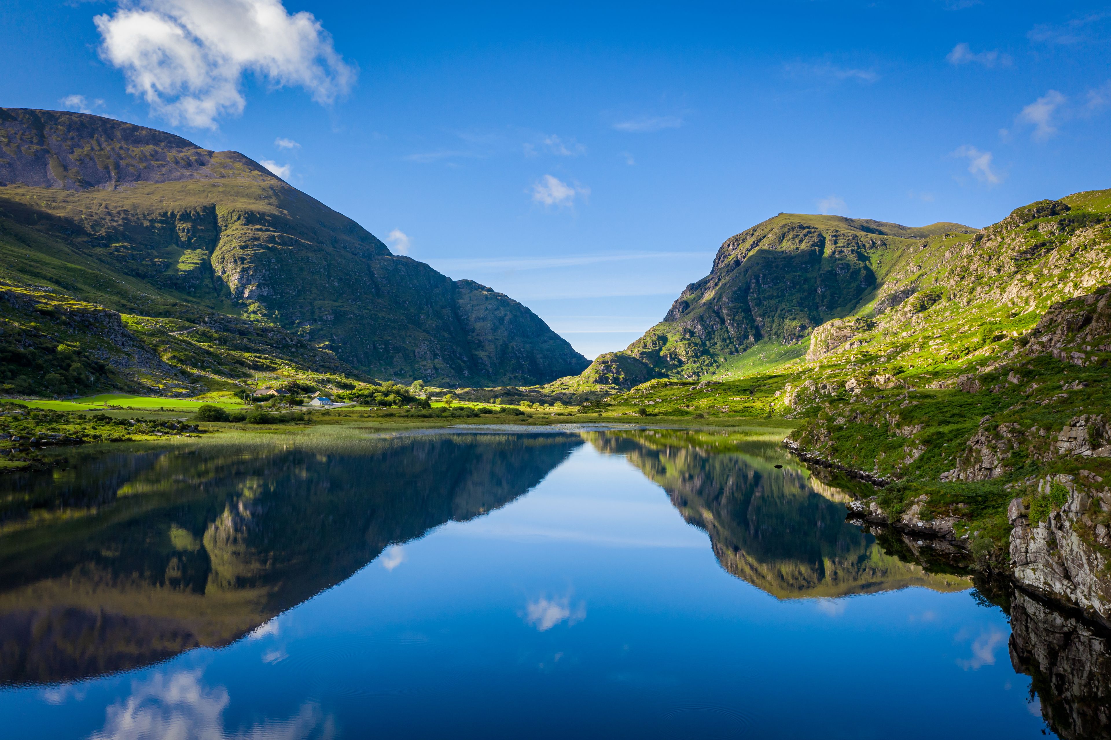 Un lac paisible dont les eaux reflètent clairement les montagnes et le ciel environnants.