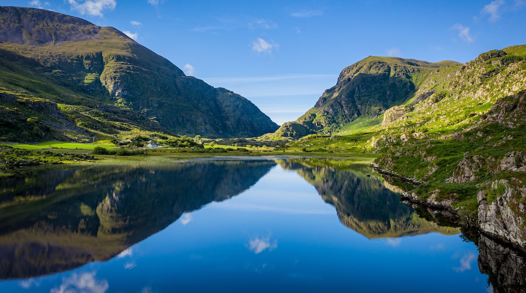 Un lac paisible dont les eaux reflètent clairement les montagnes et le ciel environnants.