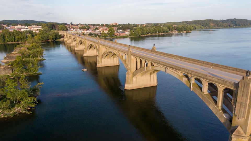 A stone bridge over a river with a town in the background.