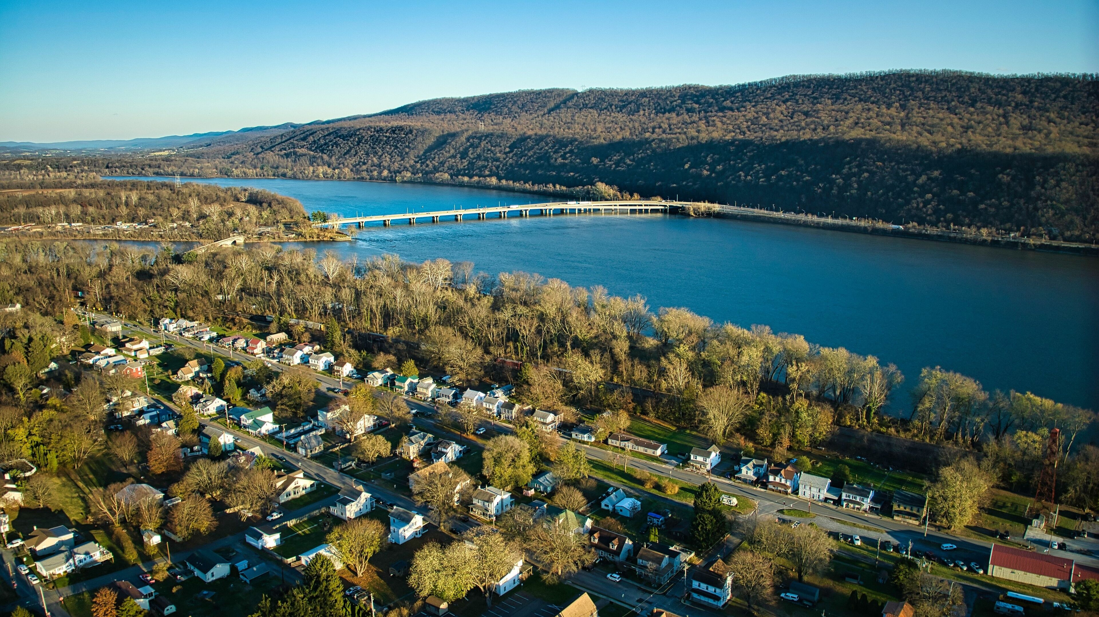 A river with a bridge, surrounded by residential areas and hills.