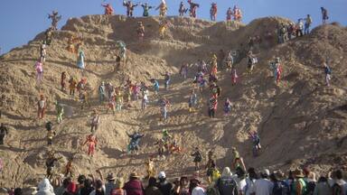 Una gran multitud de persones a un turó rocos, vestides amb indumentària colorida.