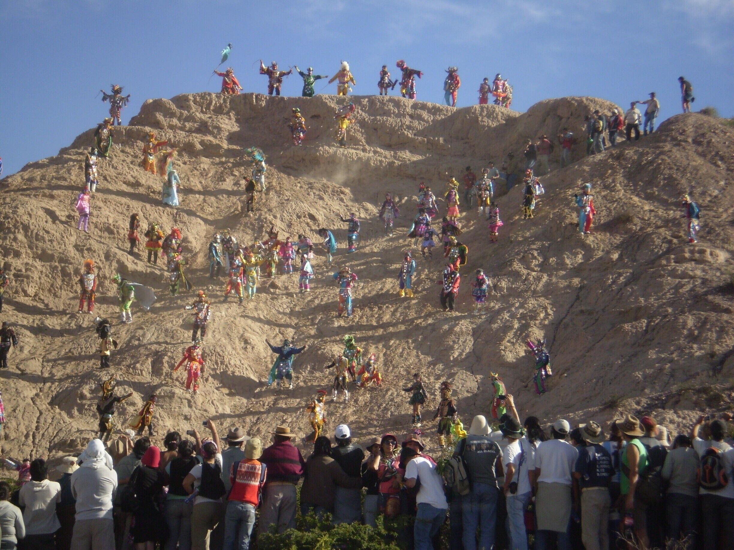 A large crowd of people on a rocky hill with colorful costumes.
