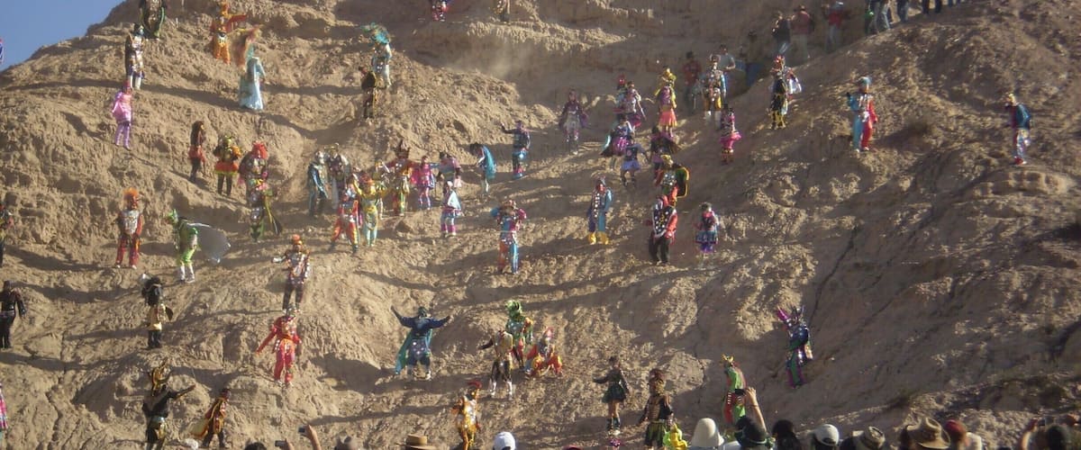 A large crowd of people on a rocky hill with colorful costumes.
