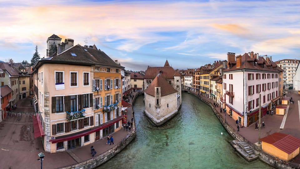 A canal in a European town with historic buildings and a tower.