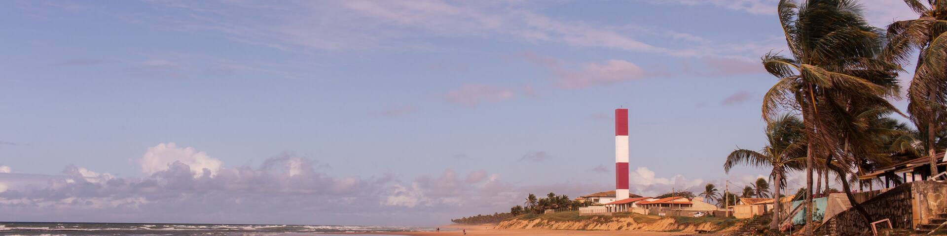 lighthouse's beach at Subauma city, cost of bahia, brazil. a person walking alone in a desert beach with view to lighthouse
