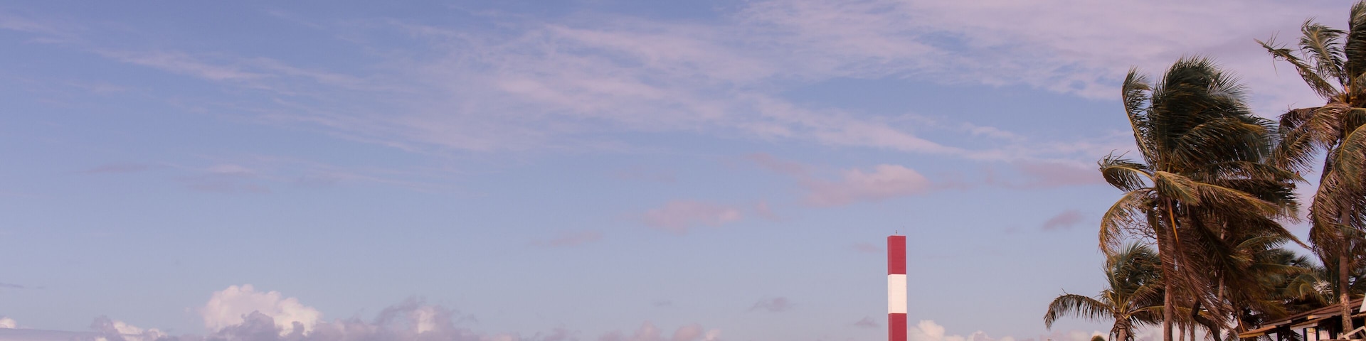 lighthouse's beach at Subauma city, cost of bahia, brazil. a person walking alone in a desert beach with view to lighthouse