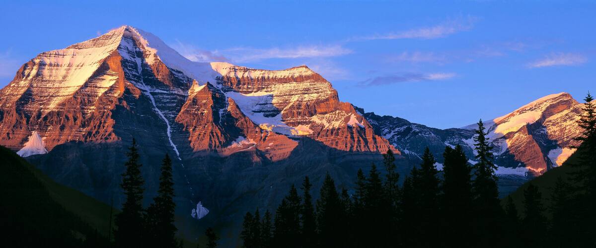A mountain range with snow-capped peaks and a clear blue sky.