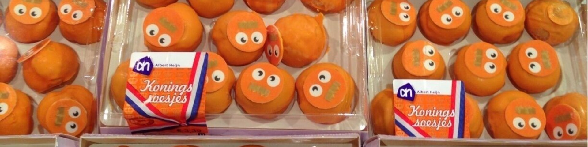 Multiple boxes of orange Konings soesjes with cartoon faces.