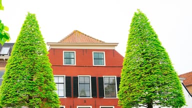 A red brick building with black shutters, surrounded by tall, green trees.