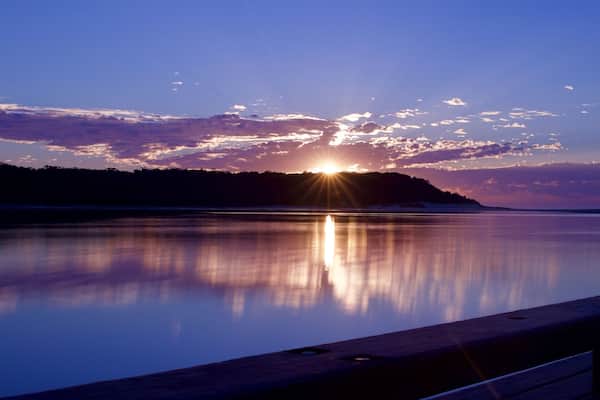 A sunset over a calm lake with a wooden dock.