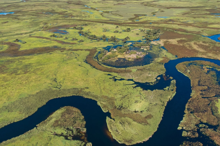 Un río serpentea por un paisaje verde salpicado de pequeñas islas y una isla central grande.
